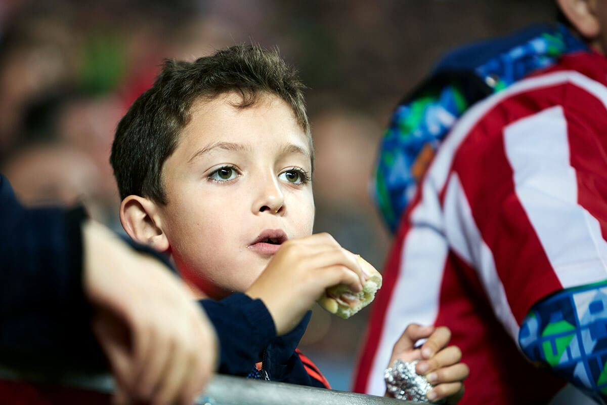 Niño mirando el partido de futbol. Fotografía de reportaje de la liga de futbol
