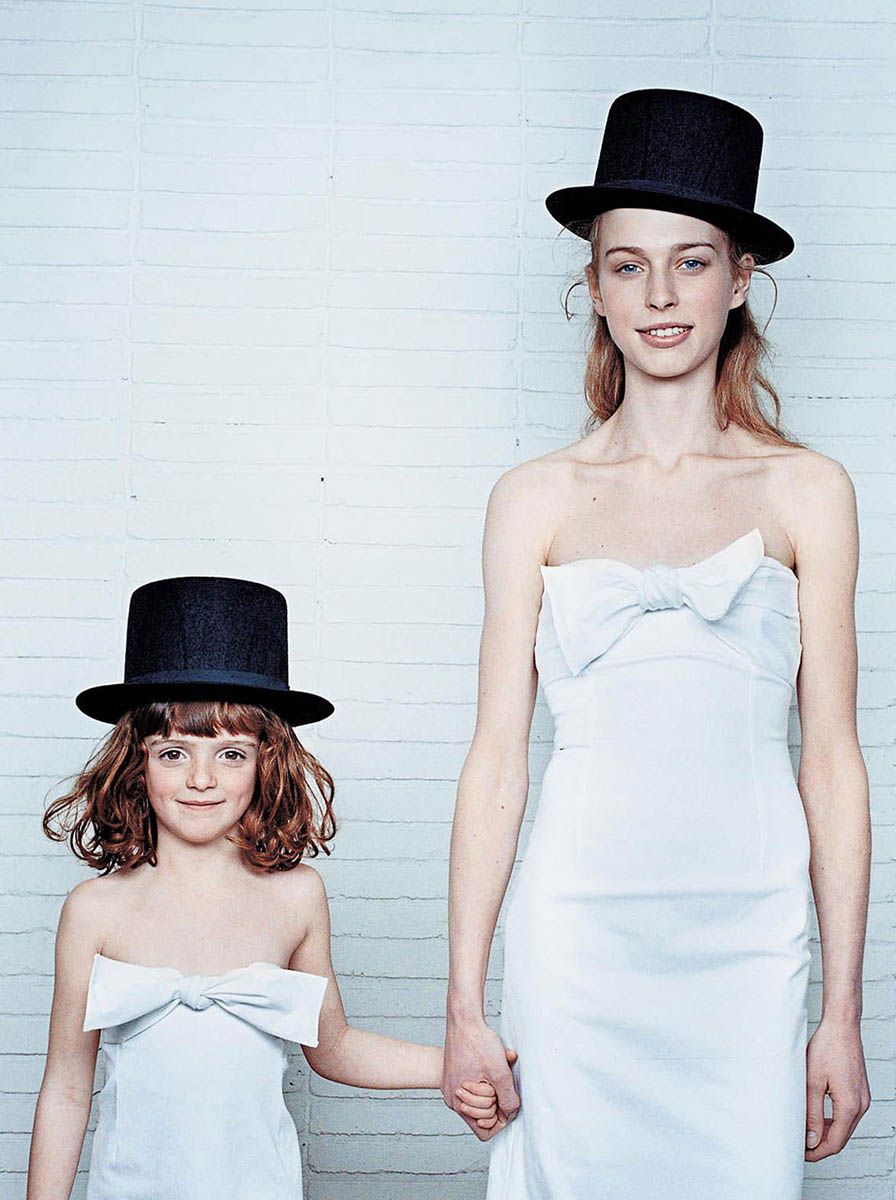 Fotografía con flash de dos modelos uniformadas con vestidos blancos y chisteras